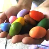 Crayons de cire Poppik forme galets multicolores tenus dans deux mains.