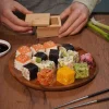 Appareil à sushi Sushi cube en bois clair avec sushi cubes colorés sur assiette ronde en bois