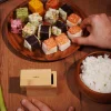 Appareil à sushi Sushi Cube Cookut en bois avec sushis cubes colorés sur assiette bois.