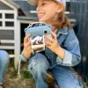 Appareil photo numérique bleu avec impression photo en rouleau, tenu par enfant en jean