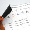 Ardoise magnétique avec nombres et mots en français, chiffres colorés, main qui décolle coin noir.