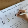 Main écrivant le chiffre 5 au feutre noir sur ardoise magnétique éducative Ferflex avec chiffres et mains dessinées.