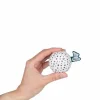 Main tenant une balle sensorielle blanche avec des petits points noirs Kaloo