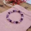 Bracelet enfant Beltane avec perles rondes roses, mauves et violettes sur pochon rose