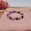 Bracelet enfant Beltane en pierres semi-précieuses violettes et roses posé sur pochette rose pâle