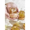 Bulle sensorielle jaune Janod avec paillettes dorées, base bois, tenue en mains.