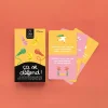 Boîte jaune et noire avec 4 micros colorés, cartes roses avec questions illustrées, jeu Ça se défend !