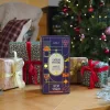 Boîte Cadeau mystère Bon vivant Cookut, design violet et géométrique, debout au sol près de cadeaux décorés
