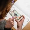 Enfant utilisant un smartphone pour animer un dessin de dinosaure coloré du Blink Book.