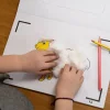 Enfant collant du coton blanc sur dessin jaune de mouton dans cahier Blink Book ferme