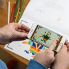 Personne utilisant un smartphone pour voir un dessin animé coloré sur cahier Blink Book.