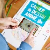 Enfant avec smartphone scannant dessin coloré sur Cahier de dessin animé La mer
