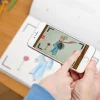 Smartphone montrant personnage animé du Petit Prince au-dessus cahier Blink Book blanc.