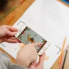 Enfant tenant un smartphone affichant une animation de renard, cahier Les Fables de La Fontaine.