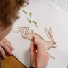 Enfant coloriant un dessin animé d'un lapin beige et feuilles vertes dans le cahier Blink Book.