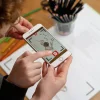 Enfant tenant un smartphone affichant un lapin animé issu du Cahier Blink Book Les fables de La Fontaine Tome 2.