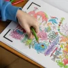 Main d'enfant coloriant des fleurs multicolores au crayon vert dans Blink Book Les mille et une nuits.