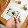 Mains d'enfant tenant smartphone sur cahier Les P'tites Poules, crayons coloriage.