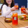 Carafe en verre avec Spritz orange, glace, étiquette Cookut, personnes trinquant.