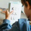 Enfant tenant cartes pédagogiques Kidydraw-mini avec lettres K en différentes polices.
