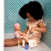 Fille jouant avec poupée et coffret Pomea brosse à dents Djeco coloré, murs verts.
