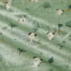 Tissu vert doux avec motifs petits chiens blancs et arbres stylisés Kaloo