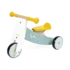 Tricycle en bois Janod bleu clair, blanc et jaune avec roues noires et poignées jaunes.