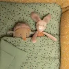 Hérisson musical en peluche beige et marron, caché sous une couverture verte à motifs