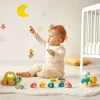 Bébé jouant avec Janod Box, jouets en bois colorés et animaux marins sur tapis blanc.