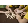 Mains jouant au Bananagrams avec lettres bois claires sur table marron