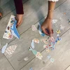 Mains d’enfants assemblant magnets marins colorés, dauphins, sirène, coraux, étoile de mer.