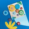 Jeu d'engrenages Les Toupitis en bois coloré avec 7 roues dentées sur fond bleu.