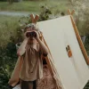 Garçon debout devant une tente beige, regardant à travers jumelles antichoc Kidybinocular noires.