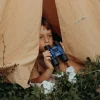 Garçon dans tente beige tenant jumelles antichoc Kidybinocular bleu et noir Kidywolf.