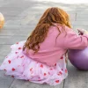 Fille dos assise jupe courte Rosalie blanche à motifs cœurs rouges et rose pâle