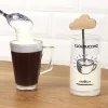 Mousseur à lait Cookut en verre avec manche nuage en bois, mousse de lait blanche, café noir dans tasse transparente.