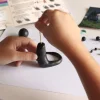 Mains modelant une sculpture noire en pâte à modeler avec un cure-dent, Kit créatif Les dragons.