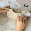 Montage d'un bateau en carton beige décoré avec étoiles dorées et voile blanche, kit Peter Pan.
