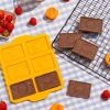 Moules en silicone jaunes et biscuits chocolatés rectangulaires Chefclub Kids sur nappe à carreaux bleus.