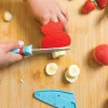 Couteau Chefclub Kids bleu et rouge en plastique, découpe banane sur planche bois.