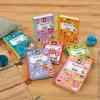 six Magnéti'book Janod colorés avec divers magnets sur table en bois clair