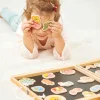 Fille tenant deux magnets jardin en bois colorés près des yeux, boîte ouverte devant.