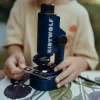 Microscope portable bleu Kidymicroscope Kidywolf utilisé par un enfant sur table fleurie.