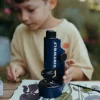 Garçon utilisant microscope portable bleu Kidymicroscope Kidywolf avec feuilles et pince.