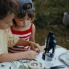 Deux enfants observent un échantillon avec le microscope portable Kidymicroscope bleu