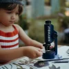 Enfant en blouse rayée rouge et blanche utilise microscope portable bleu Kidymicroscope Kidywolf.