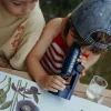 Enfant regardant dans microscope portable bleu Kidymicroscope Kidywolf avec livre ouvert nature.
