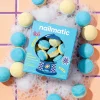 Boîte bleue Nailmatic et mini bombes de bain effervescentes bleues et jaunes sur mousse blanche