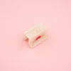 Mini pince à cheveux Coucou Suzette beige nacré avec détail doré, fond rose pâle