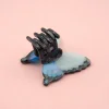 Mini pince à cheveux papillon bleu en plastique avec griffes noires.
